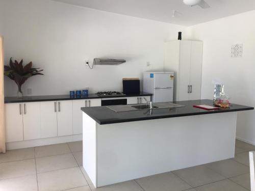 a kitchen with white cabinets and a black counter top at Ariki Dream Villa in Titikaweka
