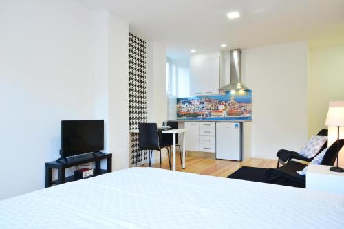 a bedroom with a bed and a kitchen with a tv at Real Home in Sacavém