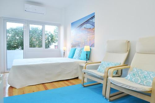 a white bedroom with a bed and two chairs at Real Home in Sacavém