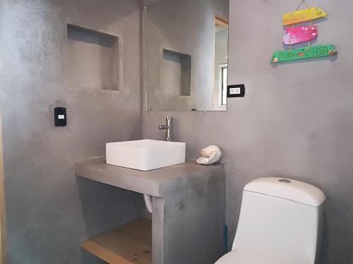 a bathroom with a white sink and a toilet at Shakti in Santa Teresa Beach