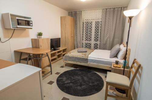een kleine kamer met een bed, een bureau en een televisie bij Bubble Apartments in Krakau