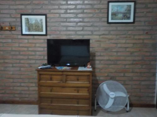 a living room with a tv and a desk with a chair at Portal del Río Posada in Santa Rosa de Calamuchita