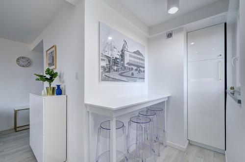 a white kitchen with a white counter and stools at Modern Place Apartament przy plaży by PIROKO in Gdynia