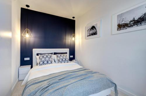 Un dormitorio con una cama con una pared de acento azul en Modern Place Apartament przy plaży, en Gdynia