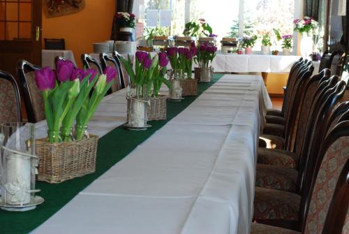 a long table with purple flowers in vases at Hotel "An der Warthe" in Salzwedel