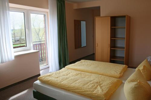 two beds in a bedroom with two windows at Hotel "An der Warthe" in Salzwedel