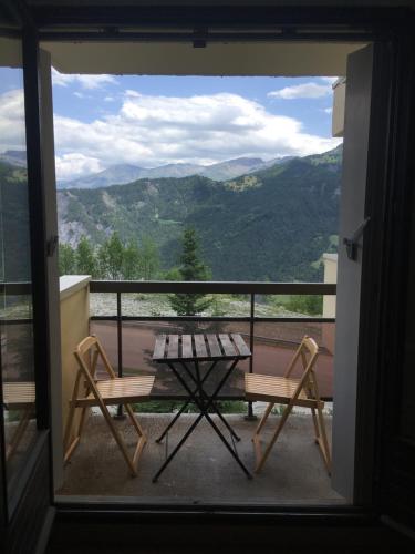 a table and chairs on a balcony with a view of mountains at Studio Praloup in Uvernet-Fours