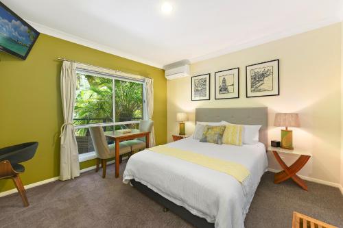 a bedroom with a bed and a window and a desk at Azura Beach House B&B in Port Macquarie