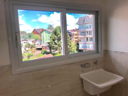 a bathroom with a large window with a sink at Apartamento no Centro de Gramado in Gramado