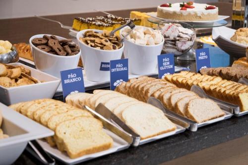 a table filled with different types of bread and desserts at Hotel Negrini in Balneário Camboriú