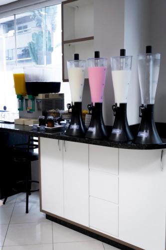 a laboratory counter with four different blenders on it at Hotel Negrini in Balneário Camboriú