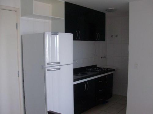 uma cozinha com um frigorífico branco e armários pretos em Varandas de Iracema 1102 em Fortaleza