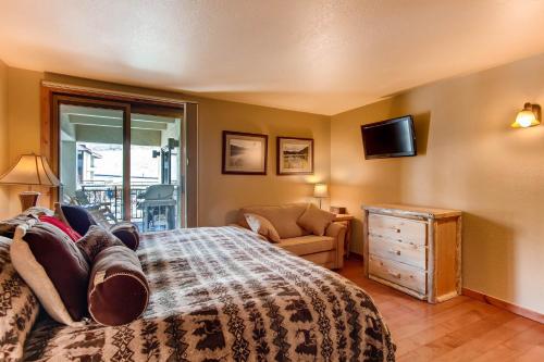 a bedroom with a bed and a television and a chair at The Plaza Condominiums by Crested Butte Mountain Resort in Mount Crested Butte