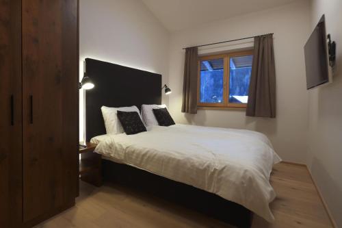 a bedroom with a bed with white sheets and a window at Alpin Penthouse Hollersbach in Hollersbach im Pinzgau