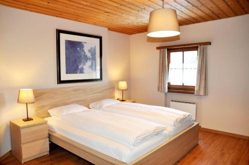 ein Schlafzimmer mit einem großen weißen Bett mit zwei Lampen in der Unterkunft Chasa Sager 5 in Scuol