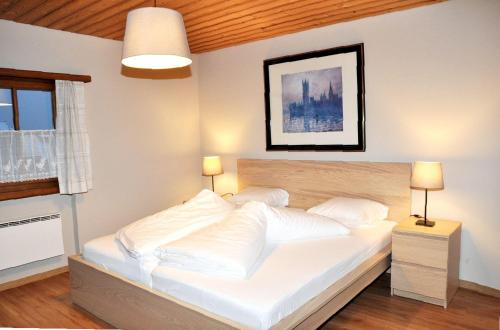 a bedroom with a bed with white sheets and pillows at Chasa Sager 4 in Scuol