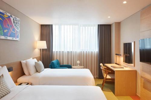 a hotel room with two beds and a desk at Howard Johnson by Wyndham Incheon Airport in Incheon