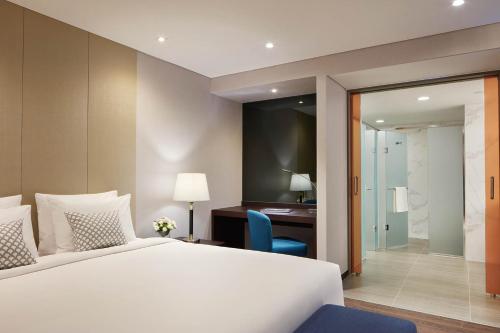 a bedroom with a large white bed and a desk and a chair at Howard Johnson by Wyndham Incheon Airport in Incheon