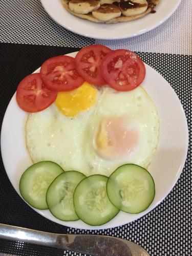 a plate with an egg and tomatoes and cucumbers at Hue Homestay Riverside in Hue