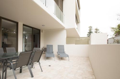 a patio with chairs and a table and a building at Bluewater Apartments in Kiama