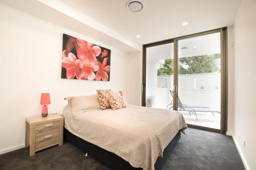 a bedroom with a bed and a large window at Bluewater Apartments in Kiama