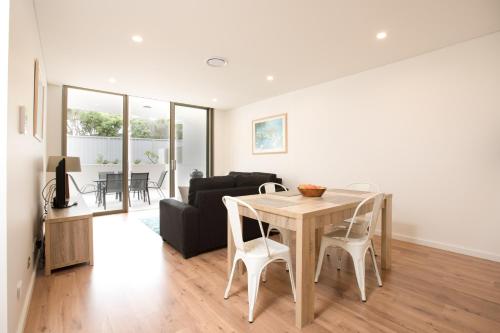 a dining room and living room with a table and chairs at Bluewater Apartments in Kiama