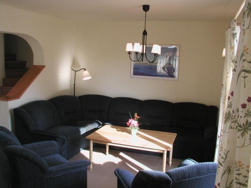 ein Wohnzimmer mit schwarzen Sofas und einem Couchtisch in der Unterkunft Gólya Villa Park in Velence