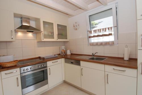 a kitchen with white cabinets and a sink and a window at Strandpark Baabe Haus 224 in Baabe