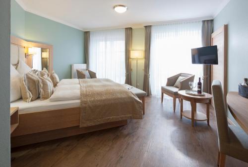 a bedroom with a bed and a table and a tv at Hotel Neuwarft in Dagebüll