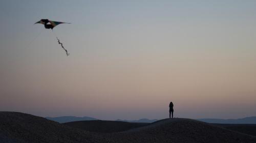 a person flying a kite on top of a hill at Desert Days mud cabin's Resort in Zuqim