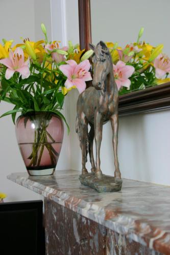 a statue of a horse on a table next to a vase with flowers at Ashmira Guest House in Weymouth