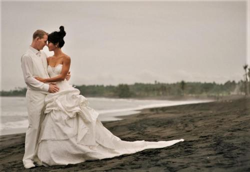a bride and groom standing on the beach at Mayo Resort in Umeanyar