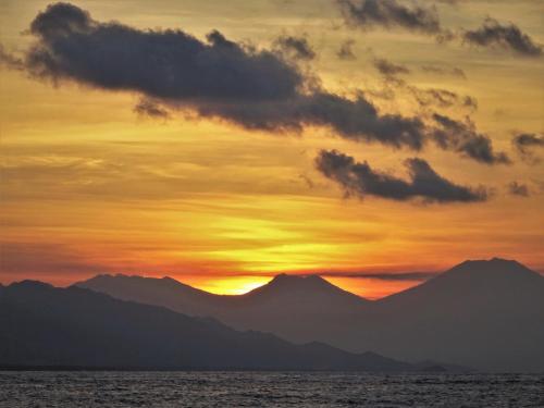a sunset over the ocean with mountains in the background at Mayo Resort in Umeanyar