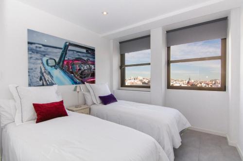 two white beds in a room with windows at Plaza España & Gran Via 2BD 1BTH in Madrid