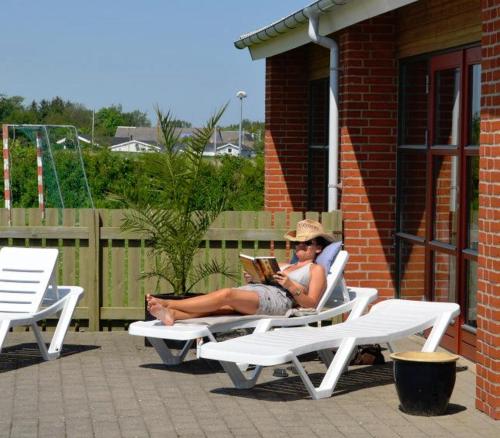 a man sitting on a chair reading a book at Frederikshavn Nordstrand Camping & Cottages in Frederikshavn