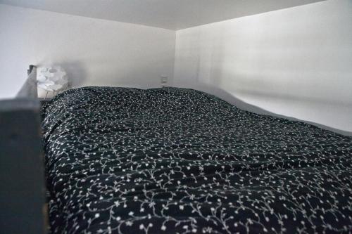 ein Schlafzimmer mit einem Bett mit einer schwarzen Bettdecke in der Unterkunft Coeur de Bastide in Bordeaux