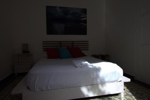 a bedroom with a white bed with red and blue pillows at La Puerta Roja Guest House in Santo Domingo