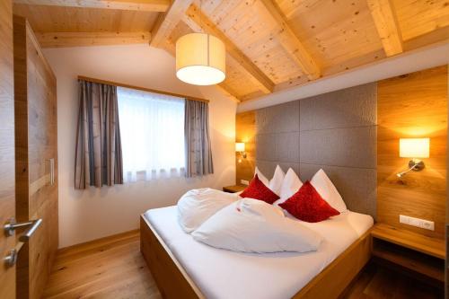 sypialnia z łóżkiem z białymi i czerwonymi poduszkami w obiekcie Chalet Schiederhof w mieście Grossarl