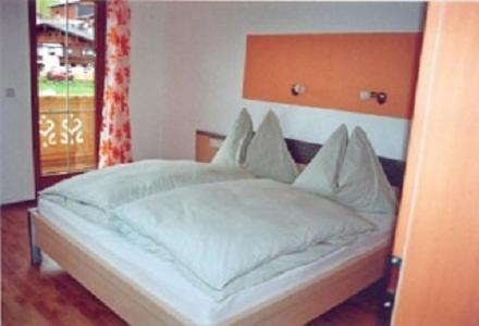 フィンケンベルクにあるFerienwohnung Eberharterの白いベッド1台(木製ヘッドボード付)が備わるベッドルーム1室が備わります。