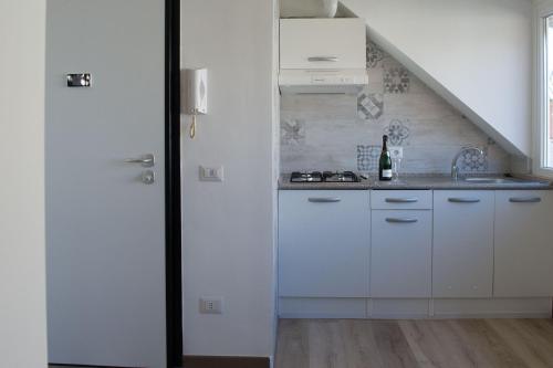 uma cozinha com armários brancos e um lavatório em Appartamento Mykonos em Lido di Ostia