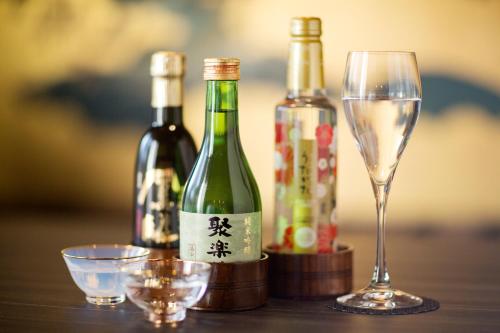 un tavolo con due bottiglie di vino e un bicchiere di Ryokan KANADE a Kyoto