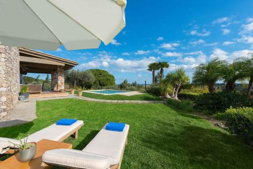AsgourouにあるBlue & Green View Villaの白い椅子2脚と傘1脚が備わる芝生