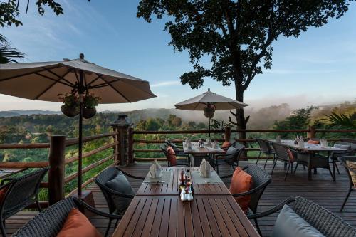 a restaurant with tables and umbrellas on a deck at Katiliya Mountain Resort And Spa in Mae Salong Nai