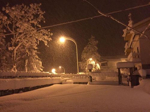 a snow covered street at night with street lights at Juliet's House in Lettomanoppello