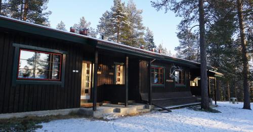 a black house in the snow next to trees at Stena Cabins & Apartments in Äkäslompolo