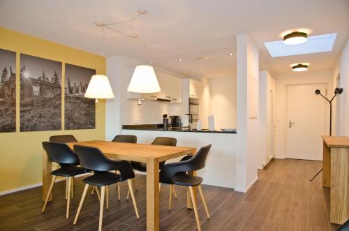 Apartment Silberdistel - GriwaRent AG في إنترلاكن: غرفة طعام ومطبخ مع طاولة وكراسي خشبية