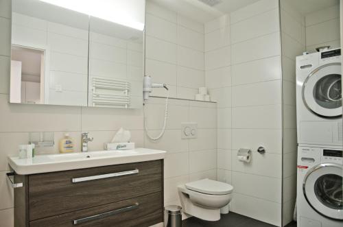 Apartment Silberdistel - GriwaRent AG في إنترلاكن: حمام مع مرحاض بالوعة وغسالة ملابس
