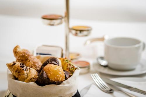 a basket of pastries on a table with a cup of coffee at Eurostars Centrale Palace Hotel in Palermo