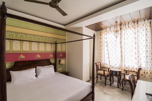 1 dormitorio con cama con dosel, mesa y sillas en Pandya Niwas en Jaipur