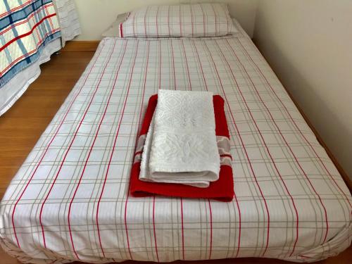 a twin bed with a red and white plaid mattress at Apartamento no Centro de Gramado in Gramado